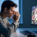 Young adult at a desk, three-quarter profile, massaging the bridge of their nose in front of a glowing computer monitor with blurred casino-like graphics, poker chips, and card backs, conveying eye strain from online gambling.