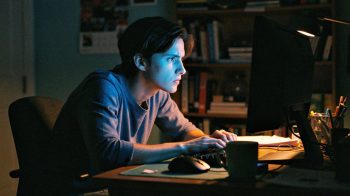 Person at a computer late at night, face illuminated by colorful screen glow